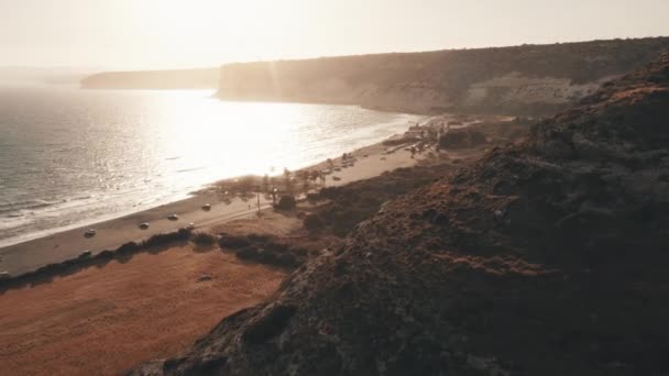 Orange solnedgång på stranden vid bergskusten. Sol skiner över åkrar gård planteringar kust — Stockvideo