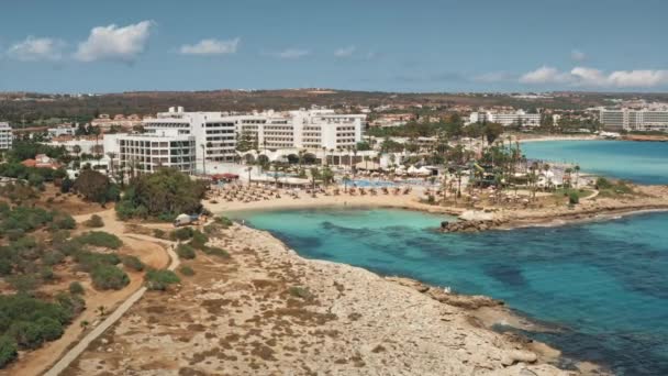 Complexo de férias de verão resort na costa do mar rochoso. Turistas relaxar na praia de areia com água azul — Vídeo de Stock