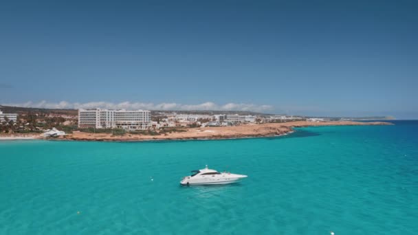 Luxe wit jacht varen in turquoise zeewater. Resort strand kustlijn op de achtergrond. Zomervakantie — Stockvideo