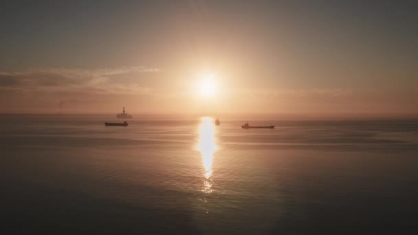 Ozeanorangefarbene Sonnenuntergangslandschaft, Frachtschiffe fahren im Abendlicht. Sonne scheint über dem Wasserhorizont — Stockvideo