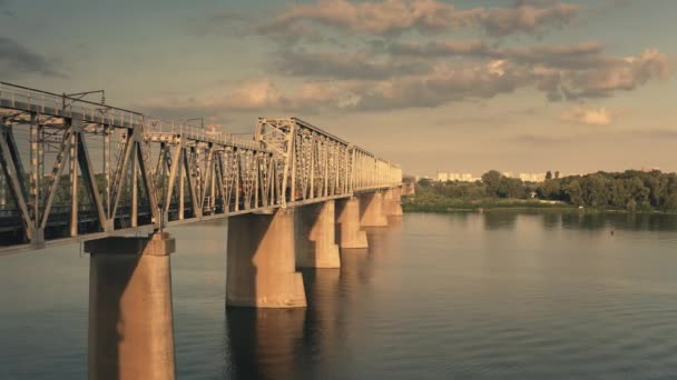 Aerial solnedgang tog krydser floden med jernbane bro. Logistisk og transport. Intercityjernbane – Stock-video