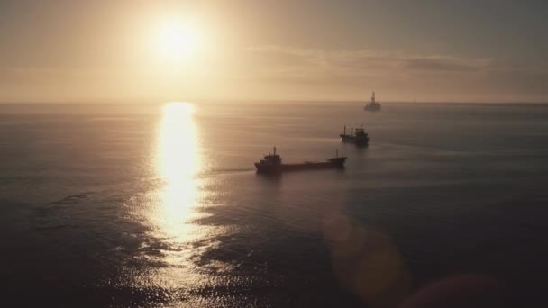 Vrachtschepen silhouet zeilen in zonsondergang oceaan. Logistiek en zeevervoer. Olieplatform — Stockvideo