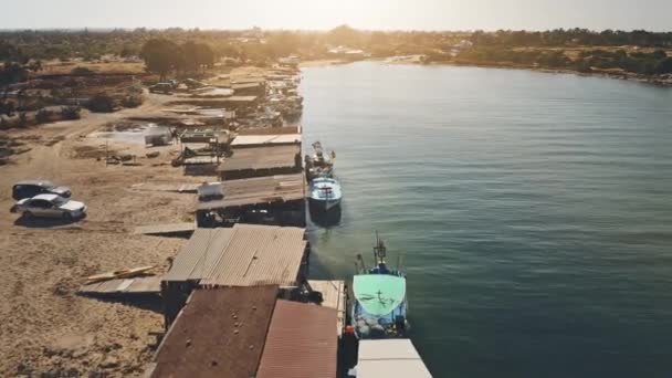 Rivieroever kust met vissersboten op pier. Luchtfoto zonsondergang natuur landschap. Zandstrand, houten schip — Stockvideo
