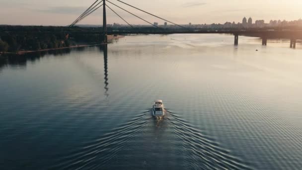 Günbatımı nehrinde yüzen büyük beyaz bir tekne. Arka planda modern şehir binaları — Stok video