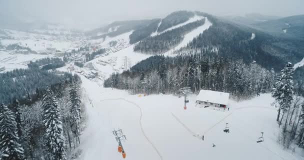 Estación de esquí de invierno en nieve Montañas de los Cárpatos. telesilla telesilla en el pico nevado, Bukovel resort pueblo — Vídeos de Stock