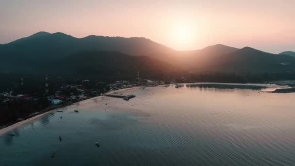 Bahía de la isla tropical al amanecer rosa. Panorama aéreo sobre muelle de playa, pueblo costero, océano tranquilo — Vídeo de stock