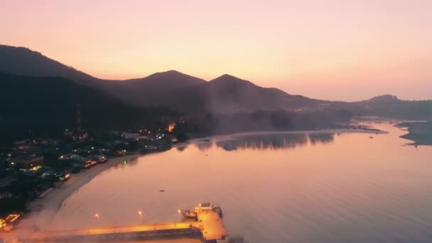 Vista aérea de la isla tropical al atardecer. Puesta de sol rosa brillante sobre el muelle de la playa, aguas tranquilas del océano — Vídeos de Stock