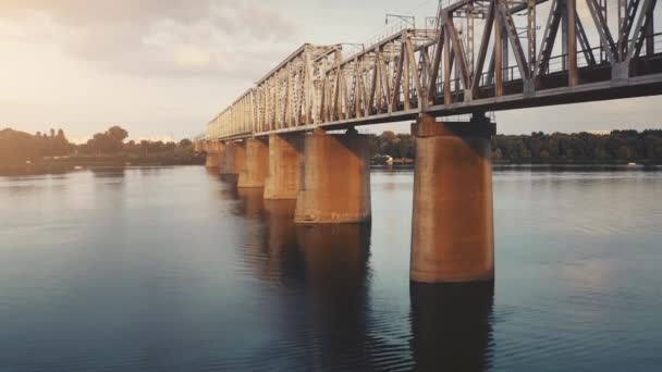 Panorama aéreo de drones del puente ferroviario al atardecer en río. Logística y transporte. Interciudad — Vídeo de stock