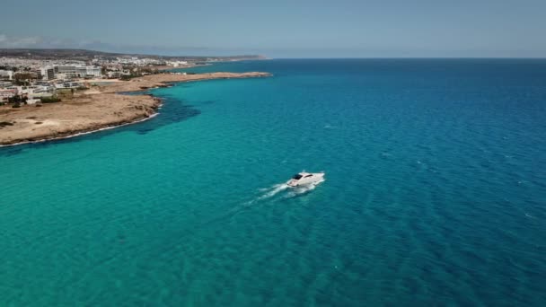 Fehér motorcsónak vitorlák közelében Ciprus partjainál kék Földközi-tenger. Nyári nyaralás koncepció. — Stock videók