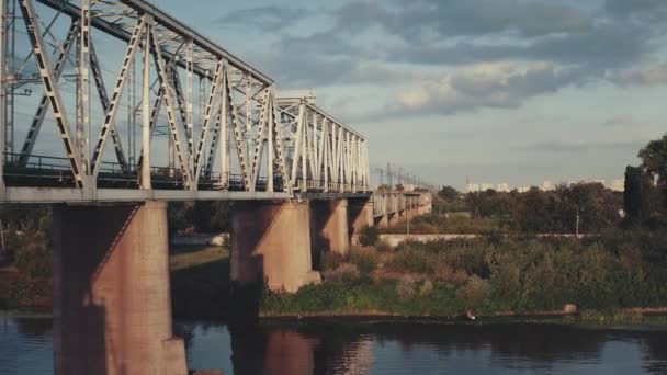 รถไฟในเมืองบนสะพานรถไฟ ภาพระยะใกล้ทางอากาศ รถไฟไฟฟ้าข้ามแม่น้ําในย่านชานเมือง — วีดีโอสต็อก