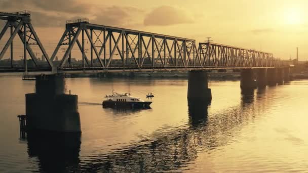 Nehir köprüsü üzerinde dramatik sarı günbatımı, endüstriyel manzara. Büyük beyaz yat yelken açıyor. — Stok video