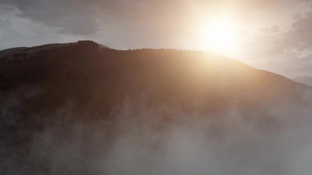 아침 안개 구름 사이로 드론이 날아가는 일출 산 정상의 공중 촬영. 안개낀 고원 — 비디오