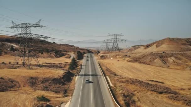 Linie wysokiego napięcia nad autostradą. Zasilanie energią elektryczną z elektrowni wiatrowych. — Wideo stockowe