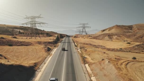 영화같은 도로 풍경. 노란 들판 과 타워가 있는 전력선, 움직이는 차들. 사막 도로 — 비디오