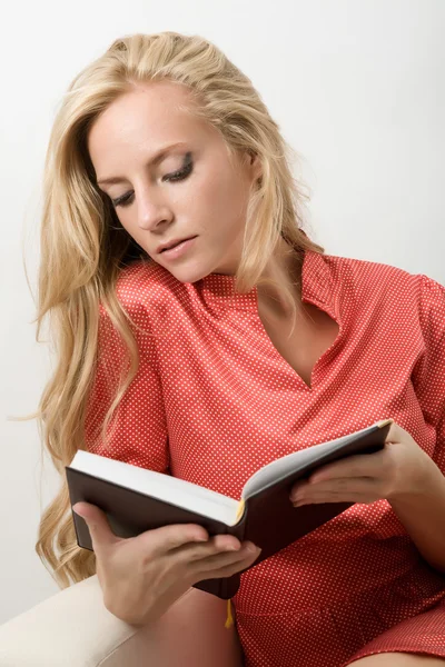 赤いドレスを着た女性が本を読んでいます。 — ストック写真