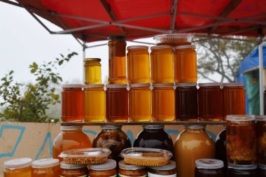 Kavanozlar dolusu organik bal tezgahta satılıktır. Farklı bal, farklı renkte cam kavanozlar bal çiftliğinde satılmaya hazır. Çeçenistan, Rusya. Kafkasya Dağı