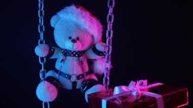 Noel Baba şapkalı oyuncak ayı BDSM oyunları için neon ışıkta zincirli bir Noel hediyesidir.