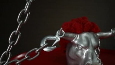 Boynuzlarında nakliye kancaları ve metal bir zincir olan bir boğa heykelciği.