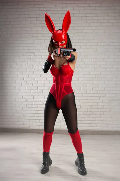 Asiatisk flicka i en röd kaninmask och en sexig röd bodysuit med ett hagelgevär i bilden av en superhjälte — Stockfoto
