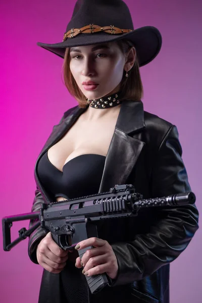 Сексуальная женщина с автоматической винтовкой в черной кожаной одежде и шляпе — стоковое фото