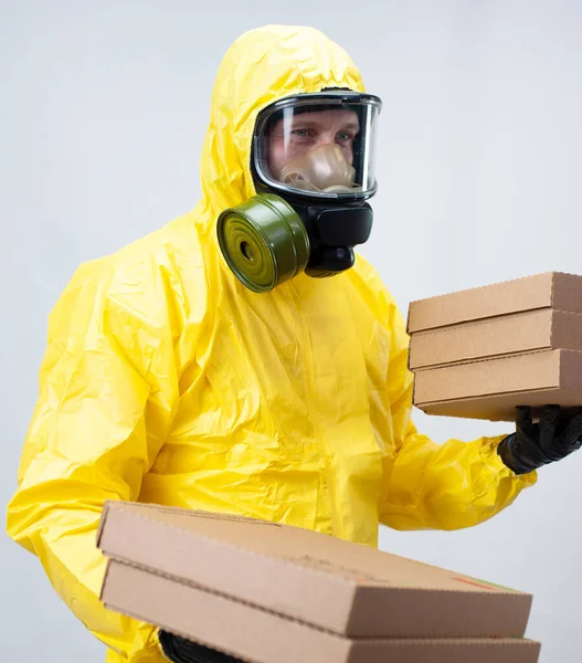 Un repartidor de alimentos en un traje amarillo y una máscara protectora de gas — Foto de Stock