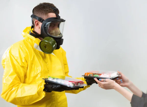 Un repartidor de alimentos en un traje amarillo y una máscara protectora de gas — Foto de Stock