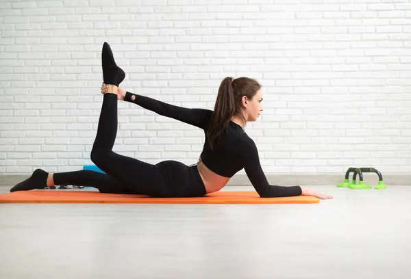 the girl conducts a home workout stretching to strengthen her back