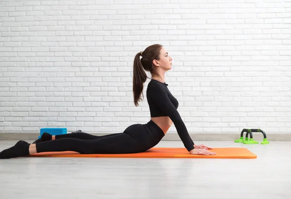 the girl conducts a home workout stretching to strengthen her back