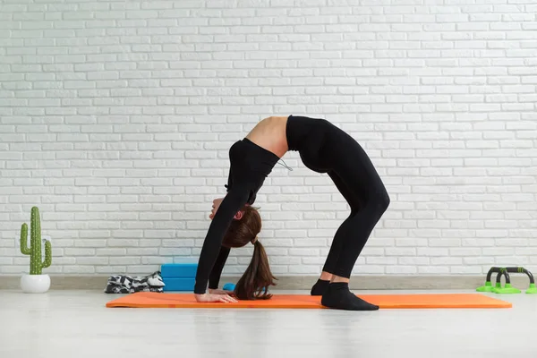 La chica lleva a cabo un entrenamiento en casa estiramiento para fortalecer su espalda — Foto de Stock