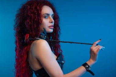 Şık bir saç stili ve elinde deri bir gül olan kızıl saçlı bir kızın portresi.