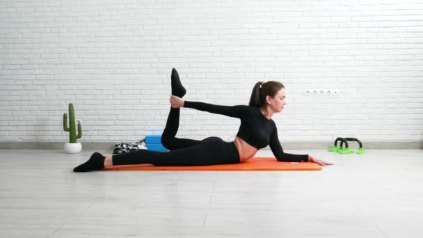 Flickan utför ett hem träning sträcker sig för att stärka ryggen — Stockvideo