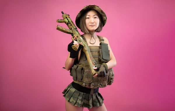 Sexy femme asiatique en vêtements militaires avec un fusil automatique dans ses mains tout en servant dans l'armée — Photo