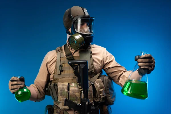 Ein Mann in Militärkleidung und Gasmaske mit chemischen Laborflaschen — Stockfoto