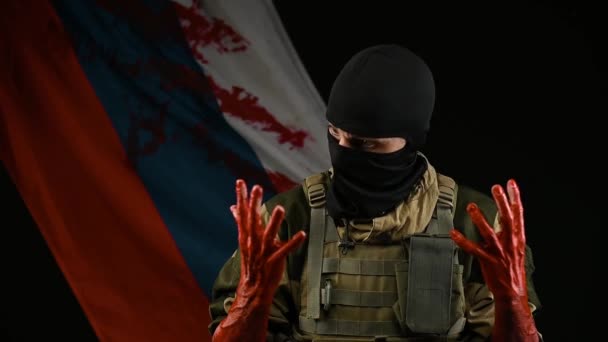 Un soldato con le mani insanguinate sullo sfondo della bandiera russa tiene la testa sotto shock — Video Stock