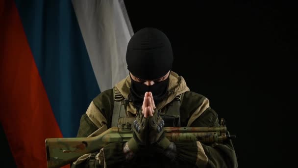 En arg rysk soldat i bakgrunden av den ryska flaggan med ett vapen i gasmask i rollen som terrorist — Stockvideo