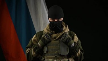 Rus bayrağının arka planında maskeli silahlı ve terörist rolünde kızgın bir Rus askeri.