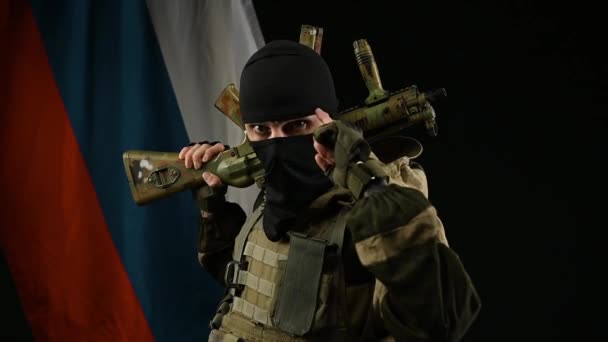 Рассерженный российский солдат на фоне российского флага с оружием в противогазе в роли террориста — стоковое видео