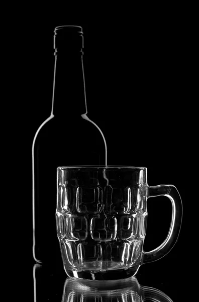 Tazza vuota e bottiglia su sfondo nero . — Foto Stock