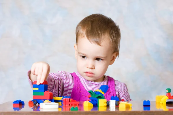 The child in a pink dress with toys — Stock Photo, Image