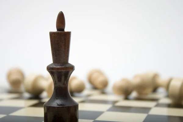 Schwarzer Schachkönig gegen weiße Figuren — Stockfoto