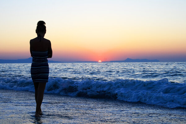 young woman as silhouette by the sea