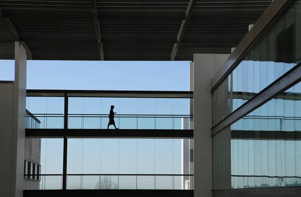 Genç kadın silueti modern ofis binası içinde yürüyüş — Stok fotoğraf