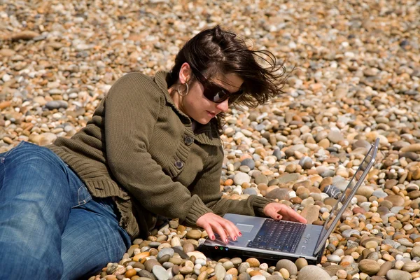 Jeune femme à la plage travaillant avec un ordinateur portable — Photo