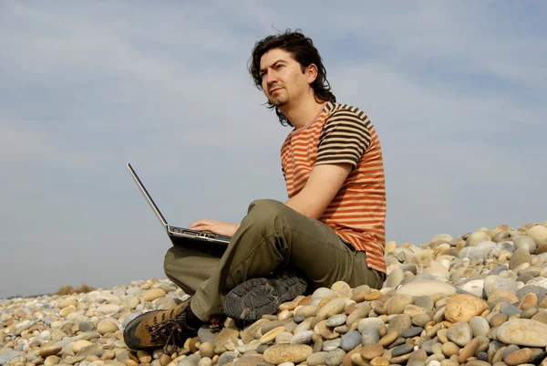 Giovane uomo casual con computer portatile in spiaggia — Foto Stock