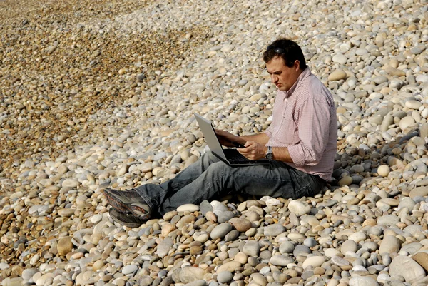 Jovem homem casual com laptop na praia — Fotografia de Stock