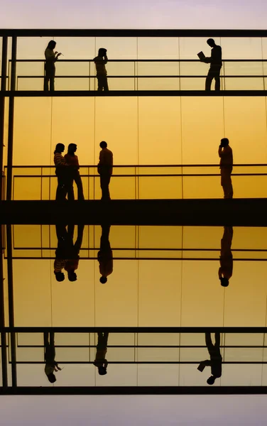 Travailleurs à l'intérieur de la silhouette de l'immeuble de bureaux au coucher du soleil — Photo