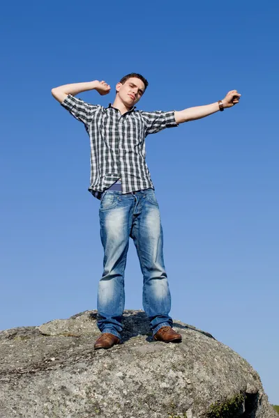 Young casual man on top of a rock — Stock Photo, Image