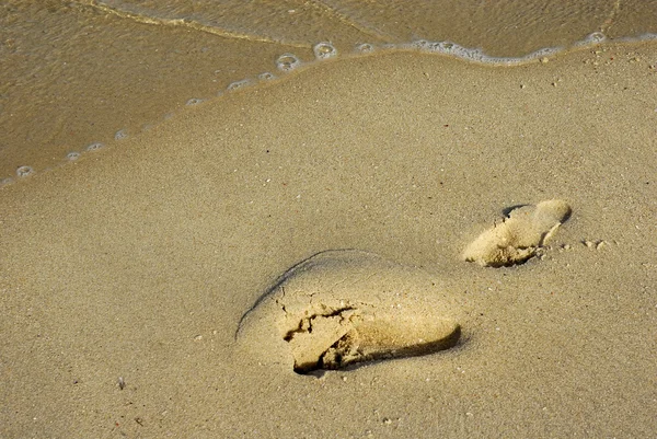 Pegada na areia e uma onda — Fotografia de Stock