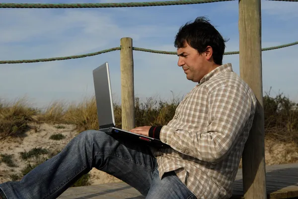 Jovem trabalhando com computador na praia — Fotografia de Stock