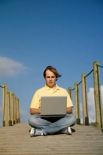 Jovem trabalhando com computador na praia — Fotografia de Stock